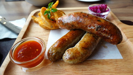 Grilled sausages served on a wooden board with dipping sauce, representing hearty comfort food, casual dining, and Western-style cuisine.