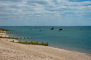 deserted pebble beach at Selsey West Sussex England with fishing boats in the background