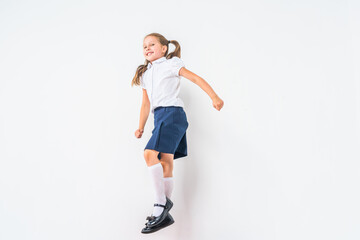 happy schoolgirl in a school uniform, jumping on a white background in the studio. the little girl is ready for school conceptual school. the holidays begin. Advertising discounts