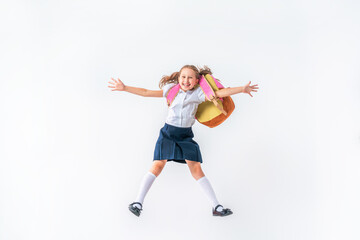 happy schoolgirl in uniform with a backpack jumps on a white background in the studio. the little girl is ready for school. conceptual school. the holidays begin. Advertising discounts
