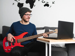 Caucasian man learns how to play bass online with his computer