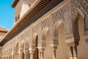 Detalle columnas y arcos ornamentados con arte árabe nazarí en el patio de los leones de la Alhambra de Granada, España - obrazy, fototapety, plakaty