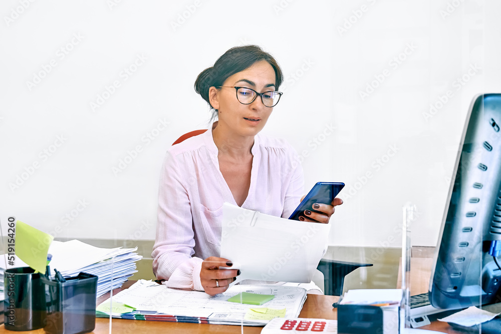 Wall mural middle-aged woman social worker check accounts bills, using smartphone to communicate or chat with t