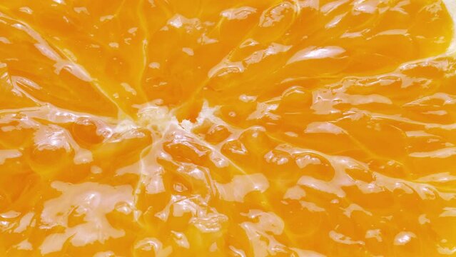 Squeezing a fresh and juicy orange. Extreme close up.