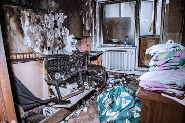 Destroyed housing after the fire, burnt things, soot and coals  everywhere