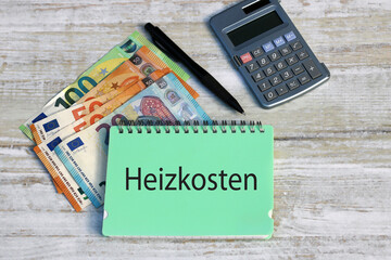 Notizblock mit dem deutschen Wort Heizkosten, mit Euro Geldscheinen und Taschenrechner.