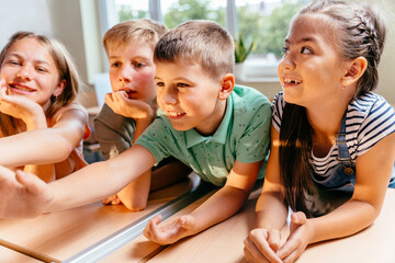 Group of children in a row enthusiastically work at the class. Cute pupils study in classroom. Friendship, interaction teamwork concept.