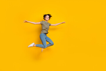 Fototapeta na wymiar Full length photo of pretty adorable girl dressed green t-shirt jumping high empty space isolated yellow color background