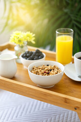 Wooden tray with breakfast on the bed