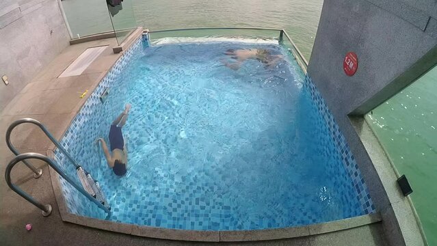 Port Dickson, Malaysia December 17, 2020 Father and son swimming in circle in a private pool in Lexis Hibiscus Hotel Resort, Negeri Sembilan. Top view.