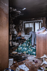 Obraz na płótnie Canvas a specialist in a protective suit from a cleaning company cleans a destroyed housing after a fire