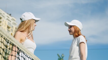 4K. The girls high-five each other and hold tennis rackets in slow motion.