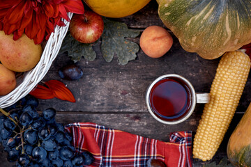Autumn rustic still life: fruits, vegetables and cup of tea: pumpkin, pears, apple, melon, grape and corn. Thanksgiving Day concept with place for text. Autumn aesthetic coziness, top view