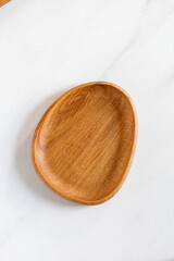 Empty oval wooden plate on kitchen table. Wooden oak dish, board, tray. Empty and template mockup with place for food. Kitchen utensils. Top view.