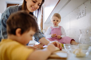 Mother of two little children preparing breakfast in kitchen at home.