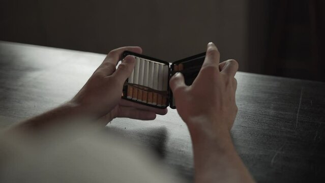 Man Anxiously Removes a Cigarette From a Case