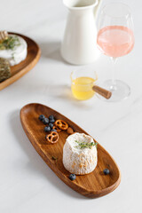 French Langres cheese on wooden plate, dish. Serving Cheese plate with nuts, berry and honey. Cheese and wine concept.