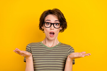 Photo of impressed funky girl dressed green t-shirt eyewear rising hands arms isolated yellow color...