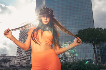 Photo shoot of stylish caucasian hip hop dancer posing standing up in orange leggings and top...