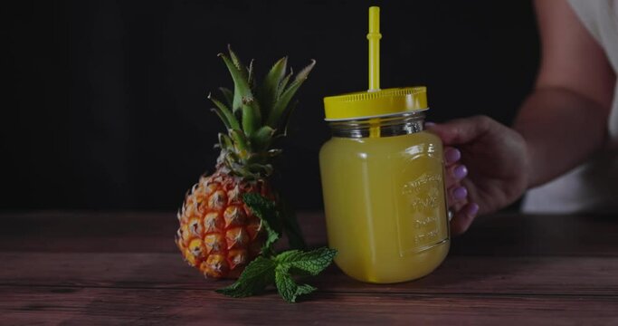 Woman's hand holding mug of natural pineapple juice.