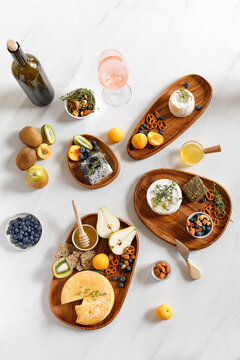 French and italian cheeses plates. Reblochon, Camembert, Caciotta, goat cheese, Langres on wooden plates with fruits and honey. Cheese plate, dish. Cheese and wine concept.