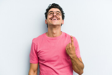Young caucasian man isolated on blue background indicates with both fore fingers up showing a blank...