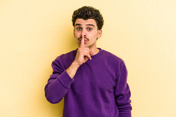 Young caucasian man isolated on yellow background keeping a secret or asking for silence.