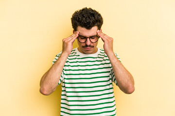 Young caucasian man isolated on yellow background touching temples and having headache.