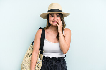 Young caucasian woman holding beach bag isolated on blue background biting fingernails, nervous and very anxious.