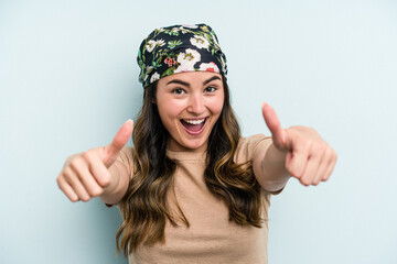 Young caucasian woman isolated on blue background raising both thumbs up, smiling and confident.