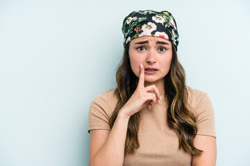 Young caucasian woman isolated on blue background looking sideways with doubtful and skeptical expression.