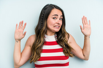 Young caucasian woman isolated on blue background being shocked due to an imminent danger