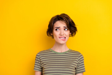 Closeup photo of unsure attractive girl looking empty space bit lip oops isolated on bright yellow color background