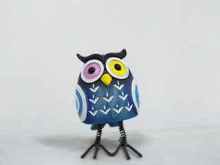A toy of a surprised blue owl with multi-colored eyes close-up stands on a white background