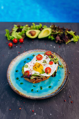 French Toast with Fried Egg , bacon, salad and tomatoes served on blue plate. Tasty Breakfast concept