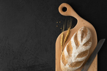 A loaf of gluten free bread on a wooden board on a black background