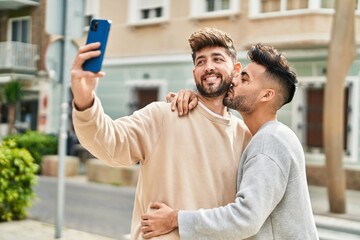 Young couple hugging each other making selfie by the smartphone at street