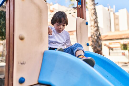 Down syndrome kid playing on slide at park