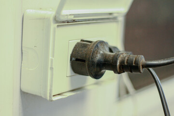 electrical switch on a wall. Black power cord cable plugged on the power outlet  box on the wall.