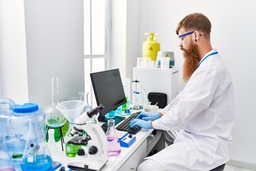 Young redhead man wearing scientist uniform working at laboratory
