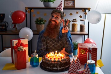 Caucasian man with long beard celebrating birthday holding big chocolate cake smiling with happy...