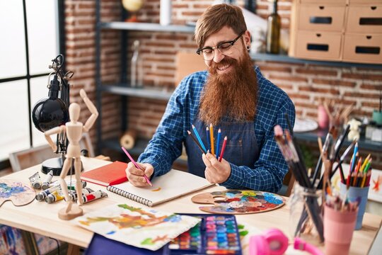Young redhead man artist smiling confident drawing on notebook at art studio