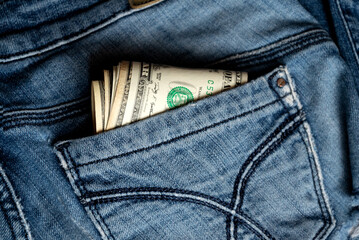 A few dollar banknotes peek out from back pocket of old jeans