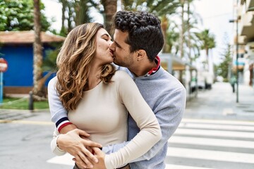 Young hispanic couple hugging in love at the city. Girlfriend and boyfriend together in love walking on the street