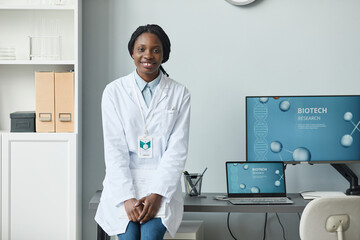 Portrait of black young woman smiling at camera while working in research laboratory, copy space