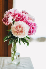 Beautiful bouquet of pink pastel peony flowers near the window.
