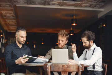 Three men are sitting at a table and talking to each other.