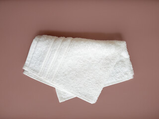 Folded white cotton towel on the beige background.
