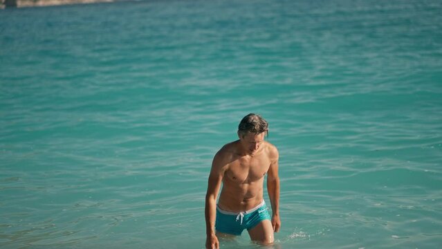 slow motion of handsome muscular athletic man in turquoise water of mediterranean sea in Oludeniz Beach in Aegean Sea after swimming. Summer tourist Season Fethiye, Mugla Turkey