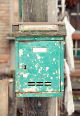 An old rusty green mailbox, hanging from a wooden post, exterior daylight shot.
